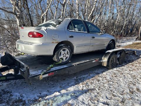 "Efficient Scrap Car Removal: Vehicle Loaded on Trailer for Recycling"